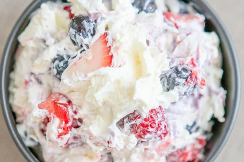 A delicious cheesecake salad topped with fresh fruits and creamy dressing