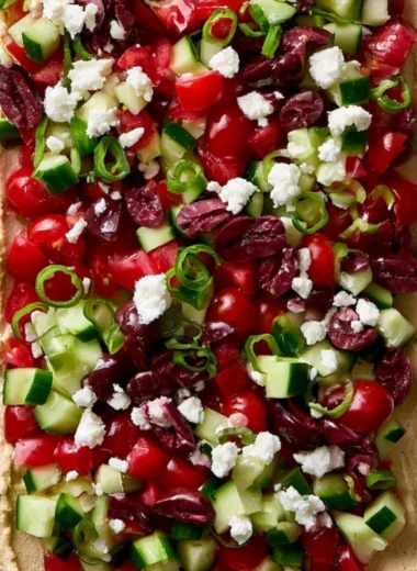 Delicious Layered Greek Dip served with pita chips and fresh veggies