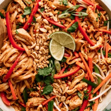 Bowl of cozy Chicken Pad Thai garnished with peanuts and lime