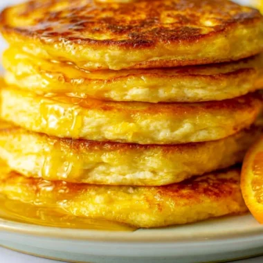 Delicious orange ricotta pancakes topped with fresh fruits and syrup.