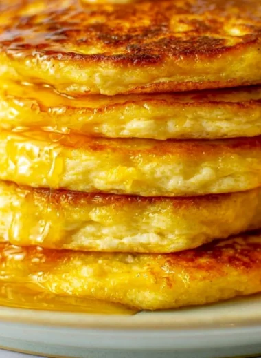Delicious orange ricotta pancakes topped with fresh fruits and syrup.