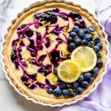 Creamy lemon tart with blueberry sauce on a white plate
