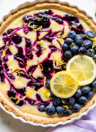 Creamy lemon tart with blueberry sauce on a white plate
