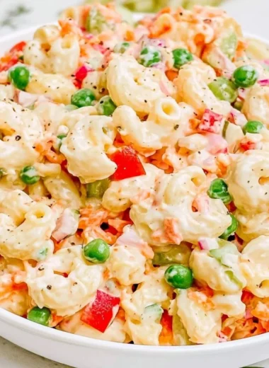 Creamy macaroni salad with vegetables and dressing in a serving bowl
