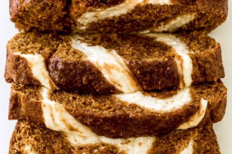 Slice of moist Pumpkin Cream Cheese Bread on a wooden board